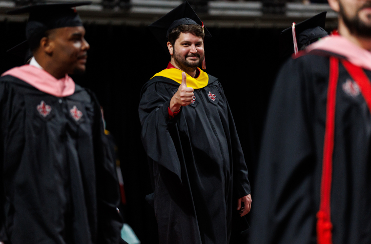 UL Lafayette graduate student in cap and gown at graduation ceremony.